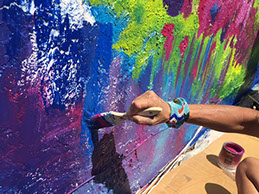 Close-up of Beth Warmath hand-painting a colorful mural